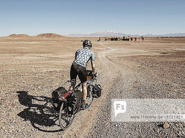 A cyclist rides through a desert toward ruins  Ouarzazate  Morocco