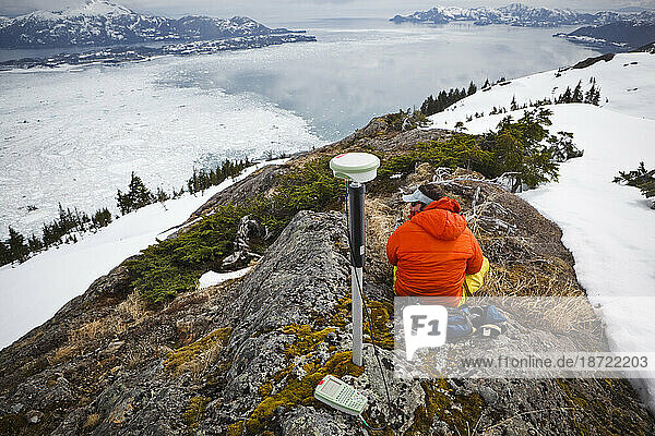 A glaciologist surveys a ground control point on a ridge above Columbia Bay  near Valdez  Alaska.