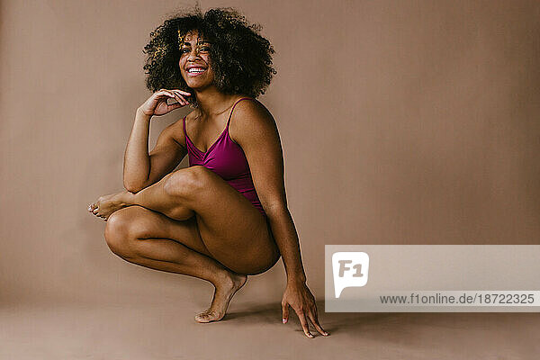 Female black dancer poses on foot with big smile and curly hair