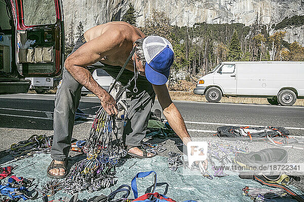 A shirtless climber sorts gear prior to a climb of El Capitan
