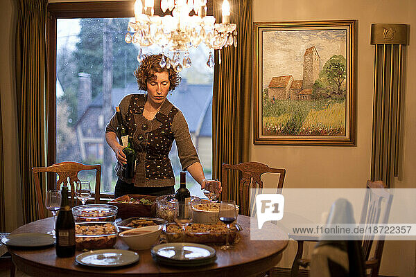 A woman sets a wine glass down on a Thanksgiving tabletop full of homemade dishes in Portland  Oregon.