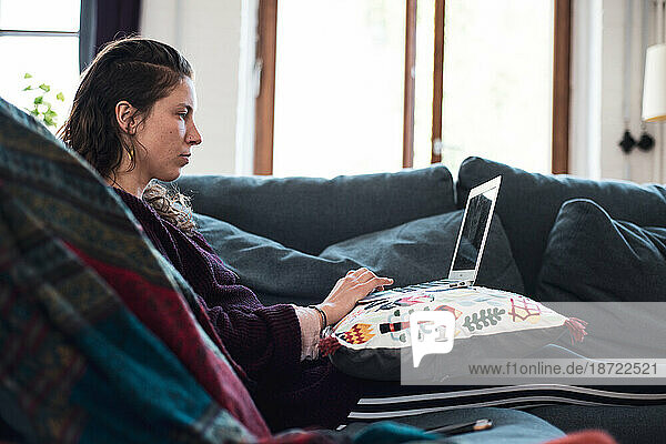 woman on laptop works from home on comfy sofa lounge