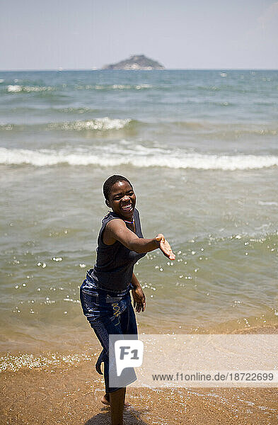 A girl laughs on the shore of Lake Malawi after being fitted by hearing aids.