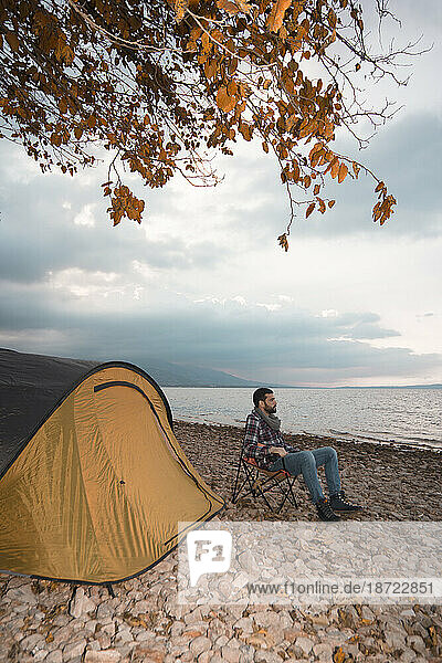 man in camp near lake  siting camp chair