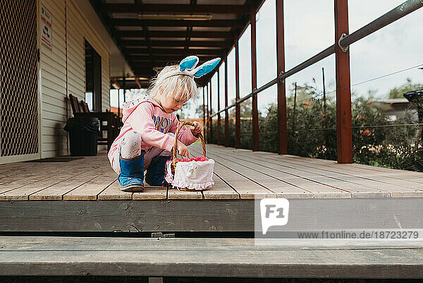 Young child collecting Easter eggs wearing bunny ears