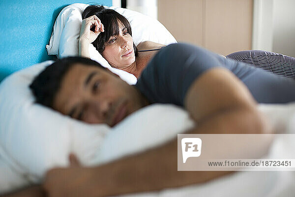 A man and woman lay awake in bed each deep in their own thoghts.