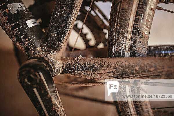 A close up of a black road bike covered in red mud