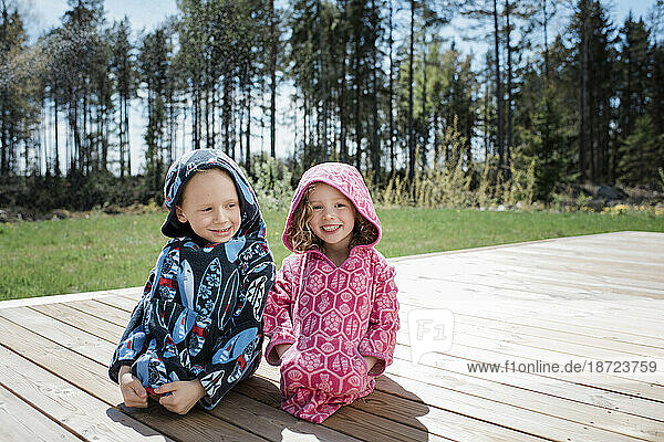 a girl and a boy sat in their swimming towels giggling at home