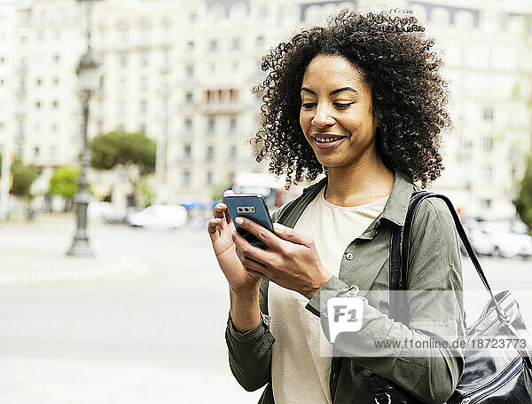 Close up smiling woman texting with his phone standing in the street.