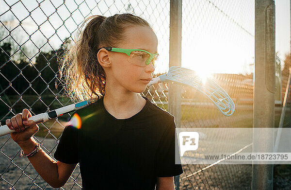 Girl holding a innebandy stick waiting to play a game at sunset