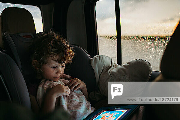 Young girl playing educational game on car ride home while it rains