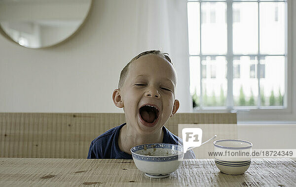 portrait of a young blonde boy laughing at breakfast time