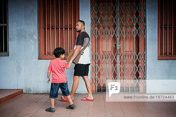 Asian man and son walking in front of shops