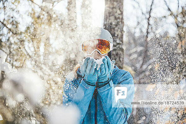 Woman in ski goggles and helmet in backlit snow scene in New Hampshire