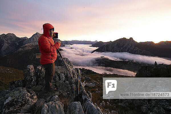 Man Photographing Mists at sunrise from the top of some mountains