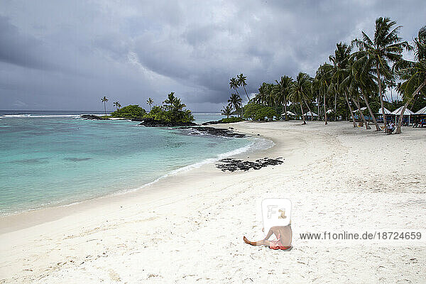 One man with hat and bathingsuit  on sandy beach of Samoa