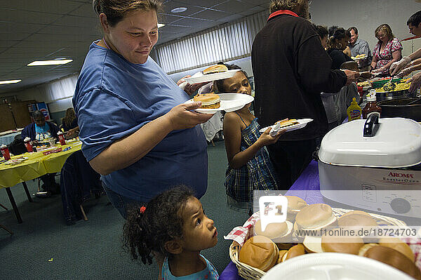 A mother and two of her girls who live in a motel on Colfax Avenue stand in line for food at a party given by an organization that helps families living in the motels  Aurora  Colo