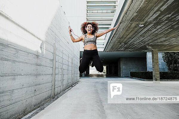 Happy Curvy African American Woman Jumping and Listening Music