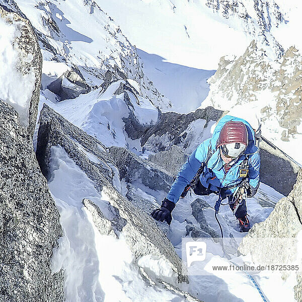 A woman mountaineer climbs a steep mixed gully on the Cosmiques Arete