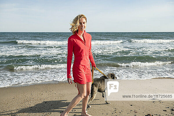 Woman in UPF sun protective clothing on beach walk with her dog