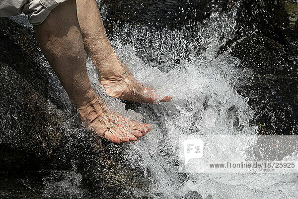 Detailed view of women cooling tired feet in a cold alpine river