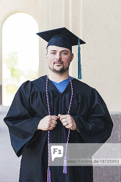 Smiling portrait of male graduate in black cap and gown