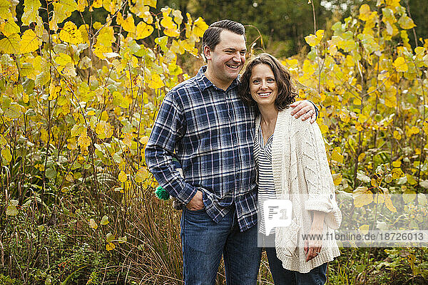 a smiling happy couple stand arm-in-arm in a golden prairie