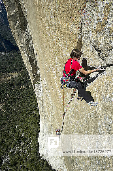 One man climbs El Cap while his climbing partner belays from a portaledge in Yosemite National Park  California.