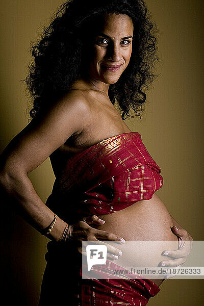 A portrait of a smiling woman who is seven months pregnant.