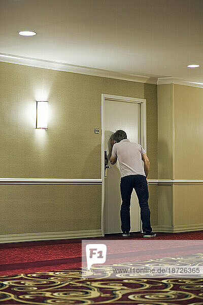 A man spies behind a hotel door in New Orleans.