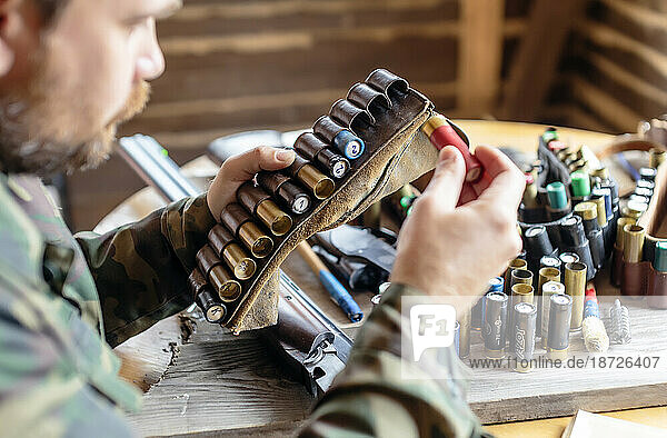 Side view of man placing shotgun shell into ammo belt  Tikhvin  Saint Petersburg  Russia