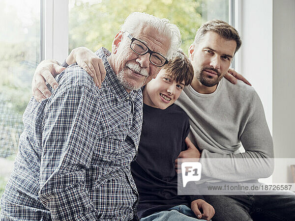 Großvater  Vater und Sohn sitzen zu Hause am Fenster