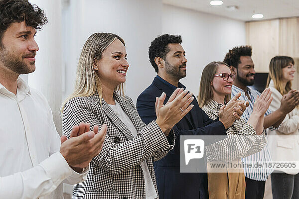 Happy business people clapping hands after a presentation in office