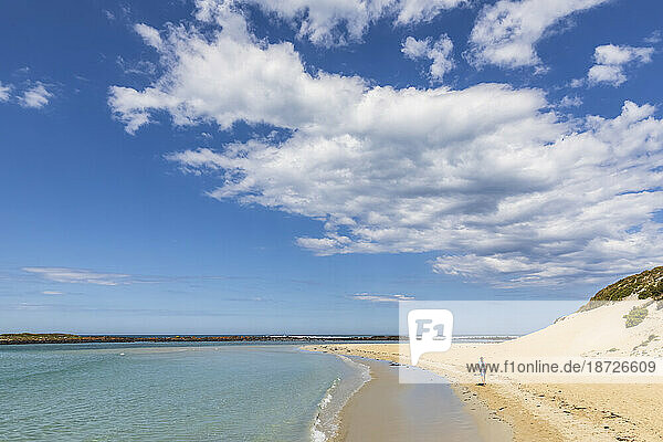 Australia  Victoria  Port Fairy  Summer clouds over female tourist hiking along sandy beach in Port Fairy Coastline Protection Reserve