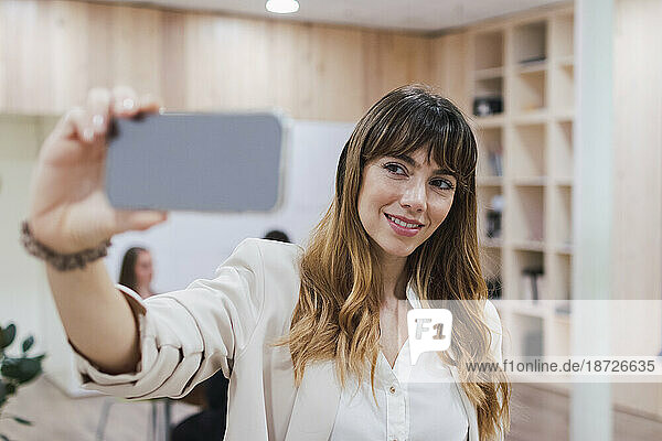 Lächelnde Geschäftsfrau macht Selfie im Büro