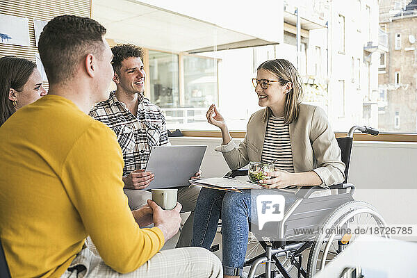 Young business people having a meeting in office with woman sitting in wheelchair