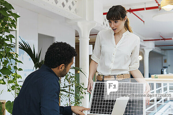 Businessman and businesswoman talking about solar panel in office