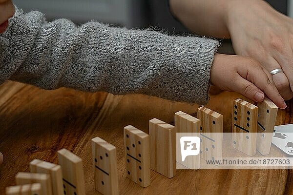 Kinderhände in grauem Pullover spielen Domino mit unscharfem Fokus