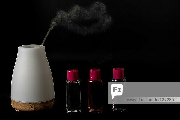 Aroma Luftbefeuchter dampfend mit Duft Töpfe vor einem schwarzen Hintergrund