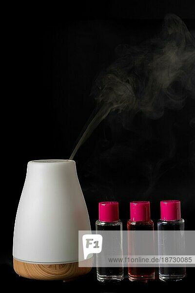 Aroma Luftbefeuchter dampfend mit Duft Töpfe vor einem schwarzen Hintergrund