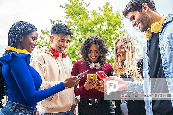Niedriger Blickwinkel auf eine Gruppe junger multiethnischer Teenager  die auf dem Campus in der Stadt Handys benutzen. Konzept einer techniksüchtigen Millennial-Gemeinschaft. Social Media Kommunikation Generation Z