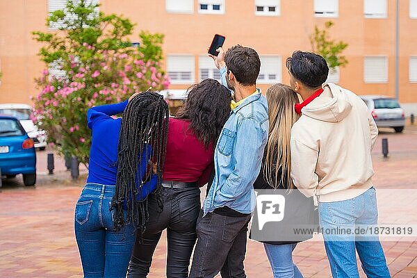 Gruppe multiethnischer Freunde  die durch den Universitätscampus spazieren und Spaß daran haben  ein Selfie zu machen  junges Millennial-Handy-Technologiekonzept