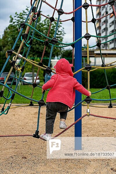 Ein kleines Kind auf dem Klettergerüst mit Netz auf einem Spielplatz