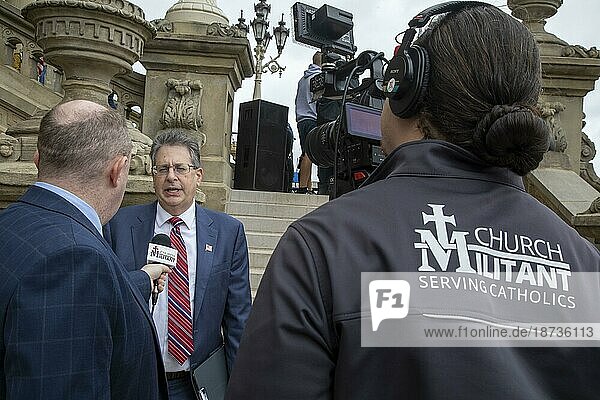 Lansing  Michigan USA  12 October 2021  A TV crew from the conservative Catholic Church Militant interviews Matt DePerno  a Trump-endorsed candidate for Michigan Attorney-General. DePerno was speaking at a rally at the Michigan State Capitol demanding a forensic audit of the 2020 presidential election results. Former President Trump charges that voter fraud was the reason he lost the election in Michigan by more than 150  000 votes