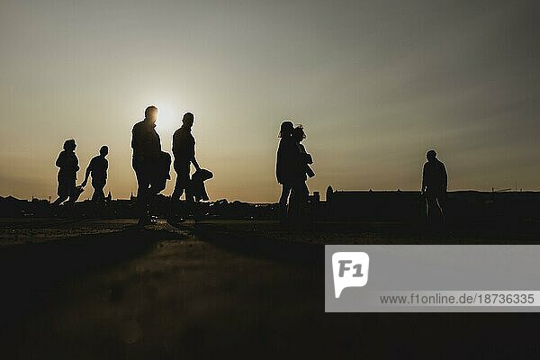 Silhouettes of walkers stand out against the setting sun on the harbour promenade in Oslo  31.05.2023.  Oslo  Norway  Europe