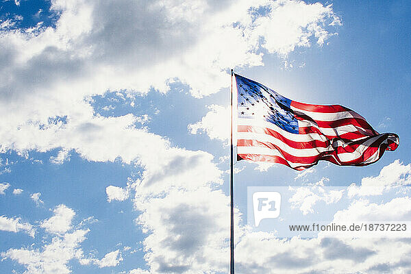 American flag blowing on wind against sky on sunny day