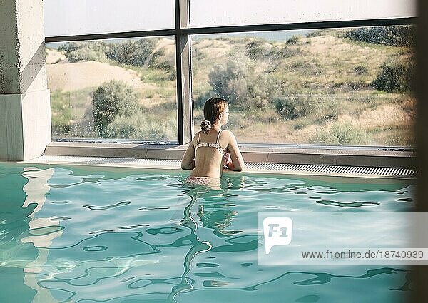 Junges Mädchen schwimmt im Pool eines Luxus Spa Center durch die großen Fenster mit Blick. Spa  Urlaub Konzept