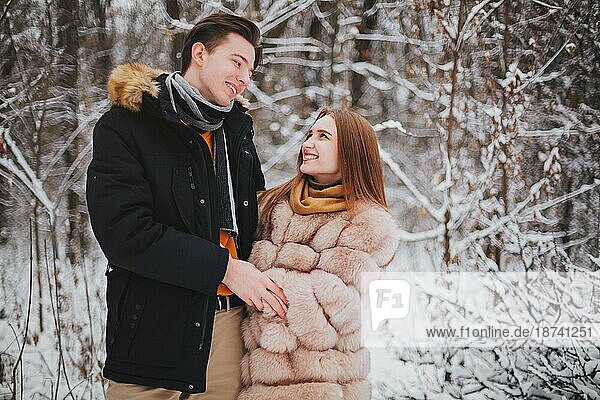 Foto von schönen jungen Teenagerpaar verbringen Zeit zusammen draußen im kalten Winter  Kerl umarmt Mädchen  um sie warm zu halten auf frostigen Tag. Romantisches Date im Freien