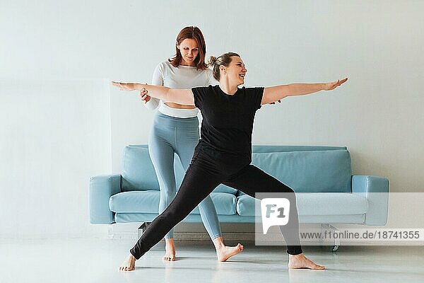 Erwachsene Frau hilft Frau in Sportkleidung mit Yogapose und Stretching Arme