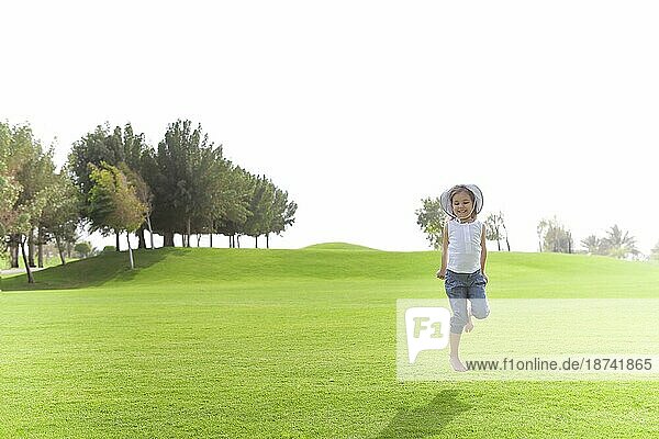 Fröhlich niedlichen Kind im Moment der Sprung über grüne Wiese im Sommer auf sonnigen Tag
